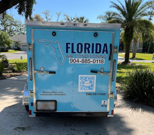 A blue trailer displaying Florida Air Conditioning, phone number, map outline, QR code, website, license number, and an About Us section is parked in a residential neighborhood.